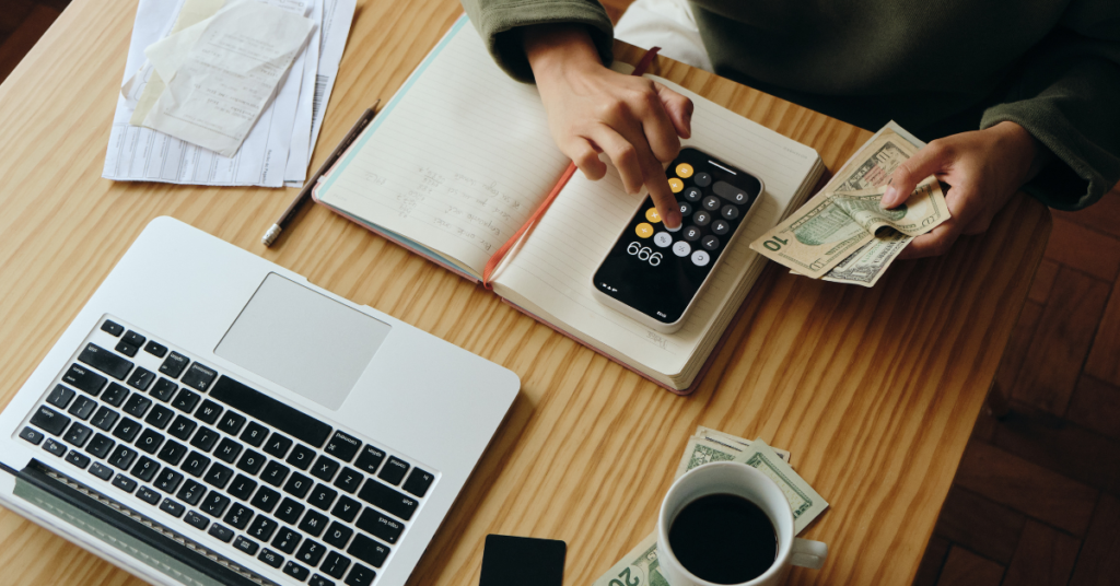 Financial planning in action with a person using calculator and notebook amidst tech devices.